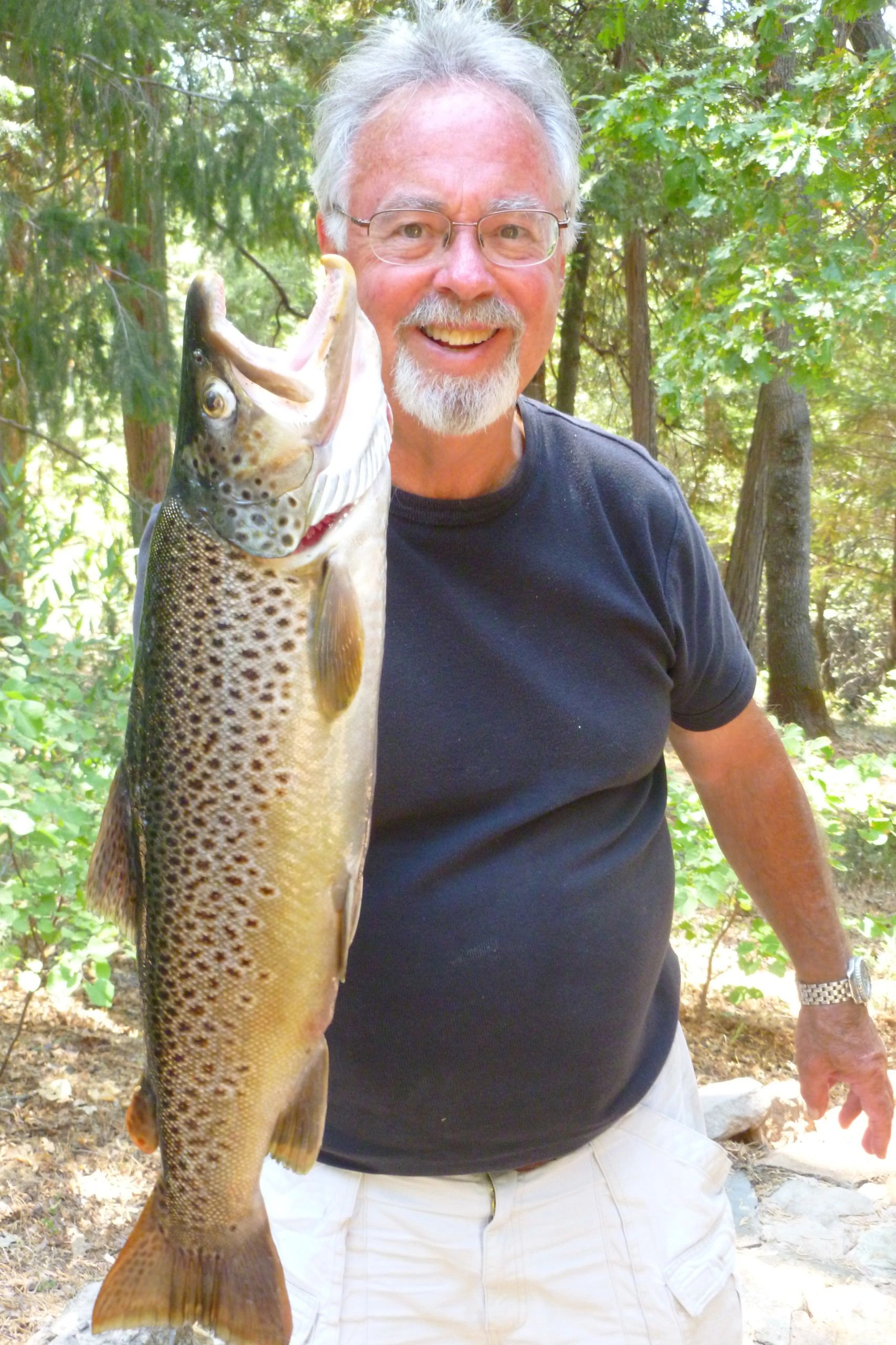 Hal Janssen holding a large spotted trout in a forest setting